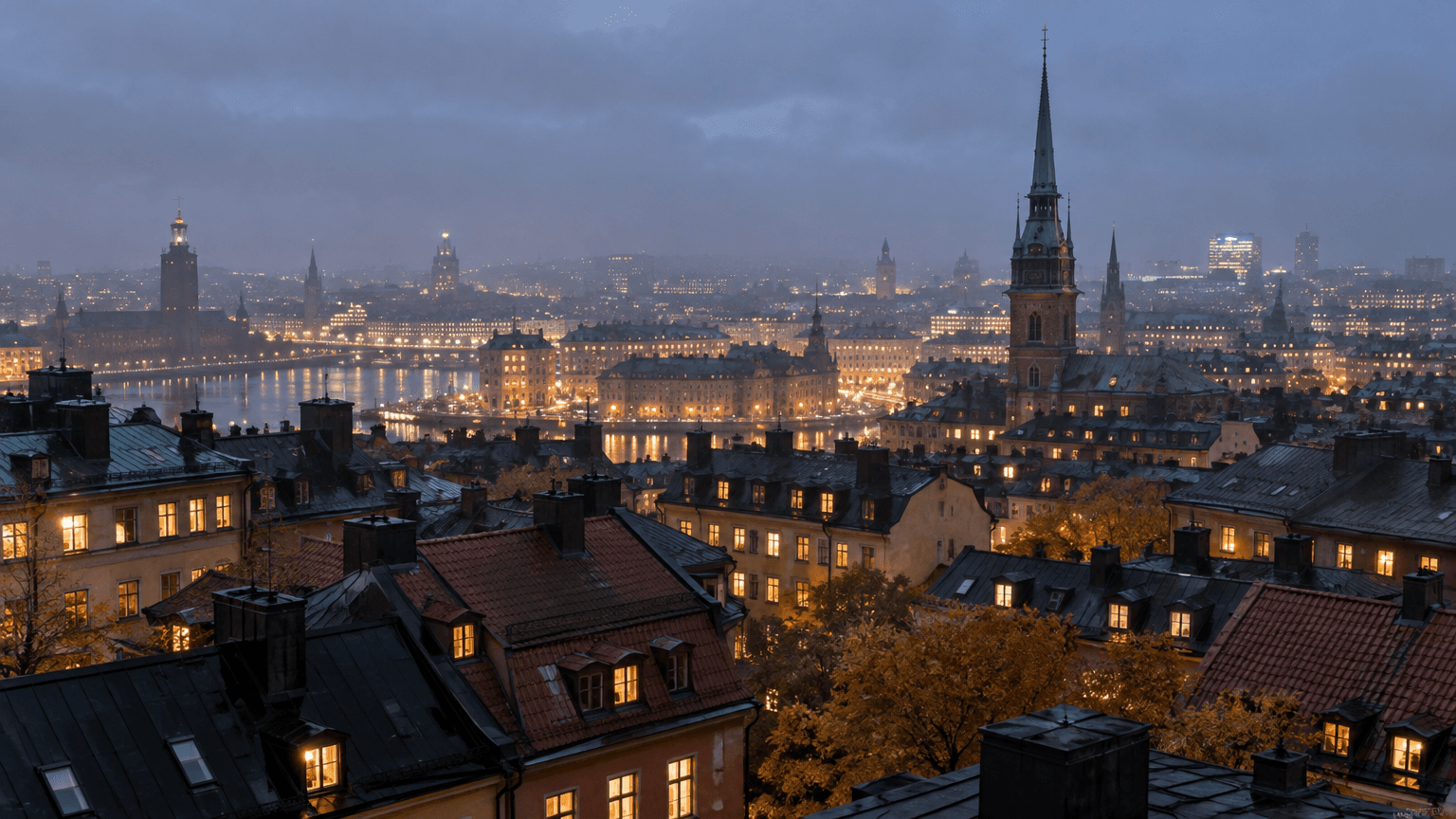 Stadens tak och kyrktorn i skymning en höstkväll med tusentals tända fönster