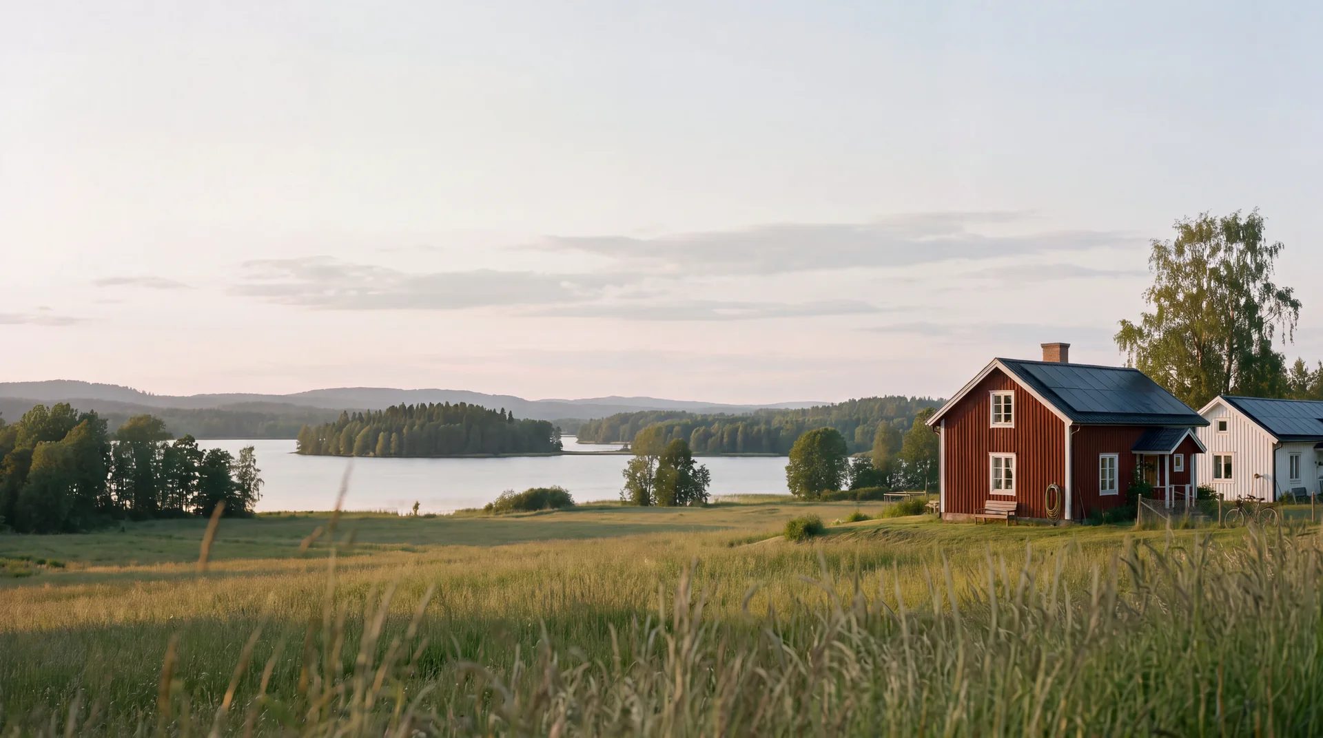 Två hus med solceller på taket vid en sjö en stilla svensk sommarkväll